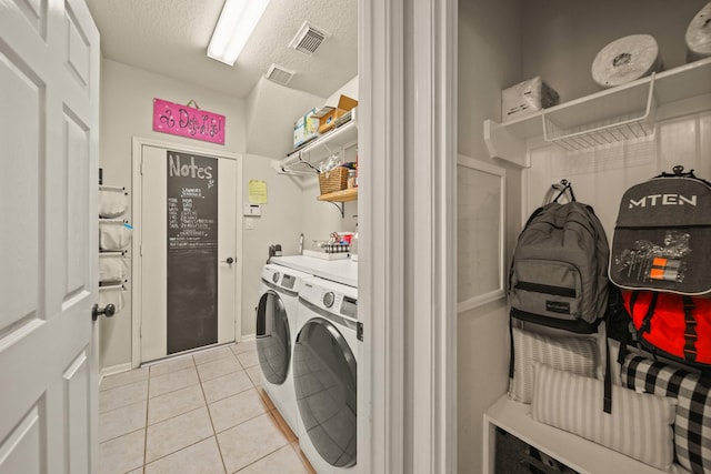 3803 Caleb Ln, Missouri City, TX 77459 - laundry area with washing machine and clothes dryer, light tile patterned flooring, and a textured ceiling