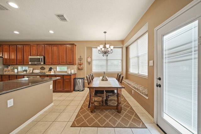 3803 Caleb Ln, Missouri City, TX 77459 - kitchen featuring stainless steel microwave, a chandelier, light tile patterned floors, pendant lighting, and recessed lighting