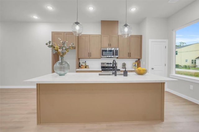8110 Brandon St, Houston, TX 77051 - kitchen featuring stainless steel appliances, light wood finished floors, light countertops, a kitchen island with sink, and pendant lighting