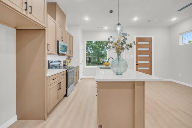 8110 Brandon St, Houston, TX 77051 - kitchen featuring stainless steel appliances, a center island, light wood-style flooring, light countertops, and pendant lighting