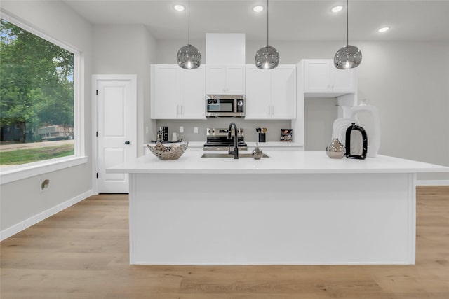 8110 Brandon St, Houston, TX 77051 - kitchen with stainless steel appliances, white cabinets, light countertops, a center island with sink, and hanging light fixtures