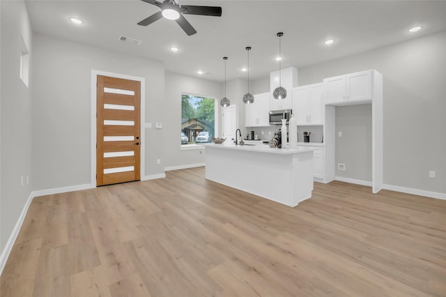 8110 Brandon St, Houston, TX 77051 - kitchen featuring stainless steel microwave, light wood finished floors, a ceiling fan, recessed lighting, and white cabinets