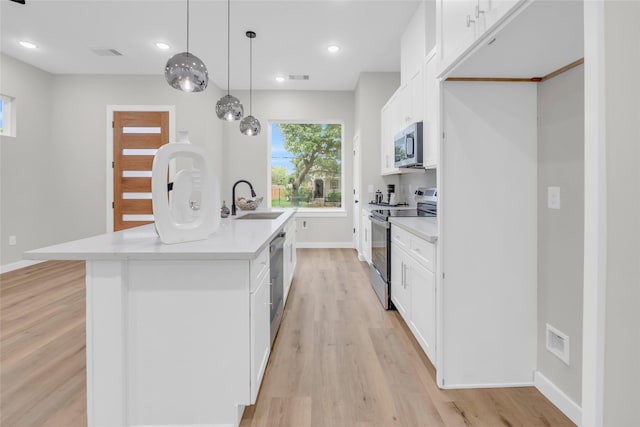 8110 Brandon St, Houston, TX 77051 - kitchen featuring appliances with stainless steel finishes, light wood-type flooring, white cabinetry, a center island with sink, and light countertops