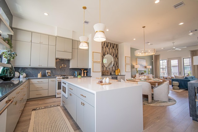 1720 Sedola Ln, Houston, TX 77055 - kitchen with white gas range oven, wood finished floors, decorative backsplash, a center island, and recessed lighting