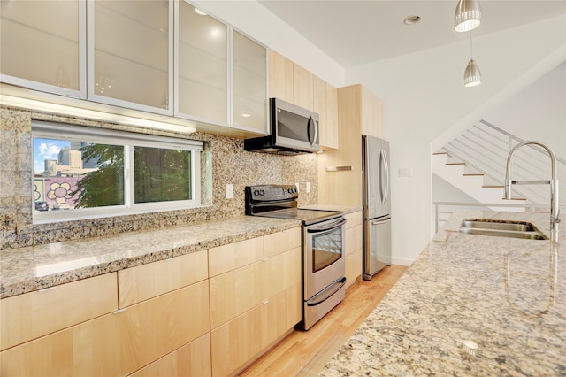 2232 Leeland St, Houston, TX 77003 - kitchen with stainless steel appliances, light brown cabinets, light stone counters, light wood-style flooring, and tasteful backsplash