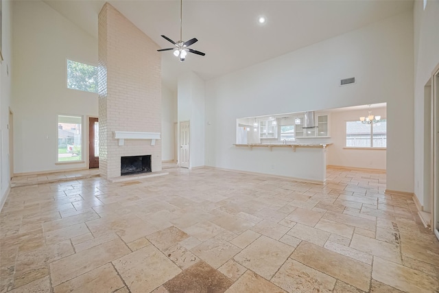 982 W Donovan St, Houston, TX 77091 - unfurnished living room with high vaulted ceiling, stone tile floors, a chandelier, ceiling fan, and a brick fireplace