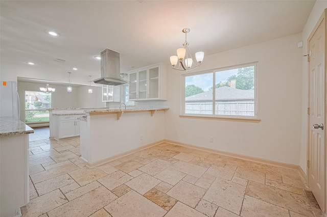 982 W Donovan St, Houston, TX 77091 - kitchen with a chandelier, freestanding refrigerator, island exhaust hood, stone tile flooring, and recessed lighting
