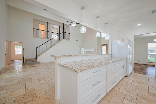 982 W Donovan St, Houston, TX 77091 - kitchen featuring stone tile floors, freestanding refrigerator, a high ceiling, plenty of natural light, and light stone counters