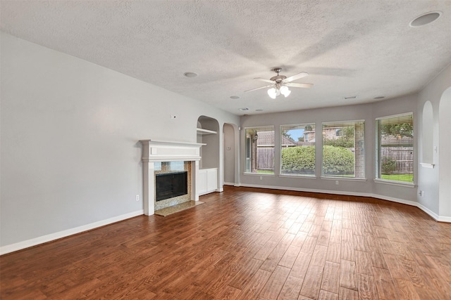 15510 Marble Canyon Way, Houston, TX 77044 - unfurnished living room featuring arched walkways, ceiling fan, wood finished floors, a textured ceiling, and healthy amount of natural light
