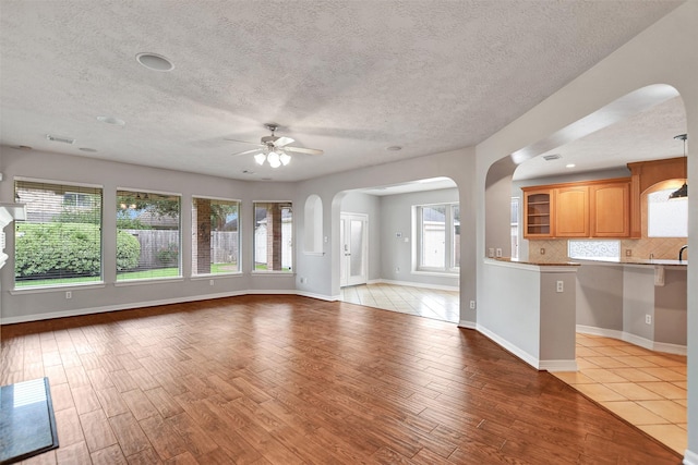 15510 Marble Canyon Way, Houston, TX 77044 - unfurnished living room featuring ceiling fan, arched walkways, light wood-style floors, and a textured ceiling