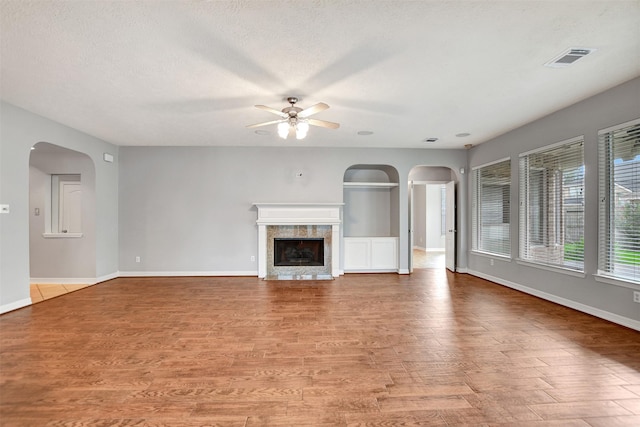 15510 Marble Canyon Way, Houston, TX 77044 - unfurnished living room with arched walkways, ceiling fan, light wood-style floors, a premium fireplace, and a textured ceiling