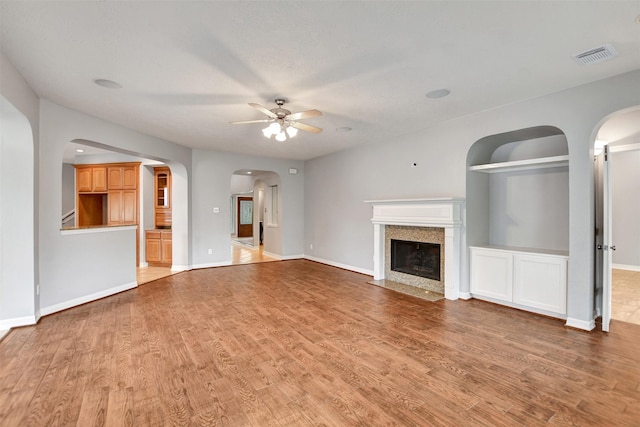 15510 Marble Canyon Way, Houston, TX 77044 - unfurnished living room featuring arched walkways, a ceiling fan, light wood-style flooring, and a premium fireplace