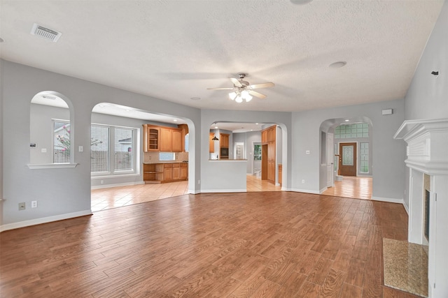 15510 Marble Canyon Way, Houston, TX 77044 - unfurnished living room with ceiling fan, light wood finished floors, a textured ceiling, and arched walkways