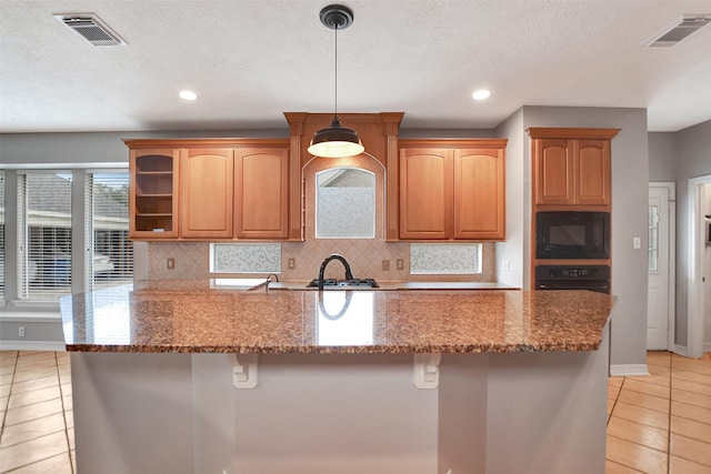 15510 Marble Canyon Way, Houston, TX 77044 - kitchen with black microwave, light tile patterned floors, dark stone counters, a kitchen breakfast bar, and recessed lighting