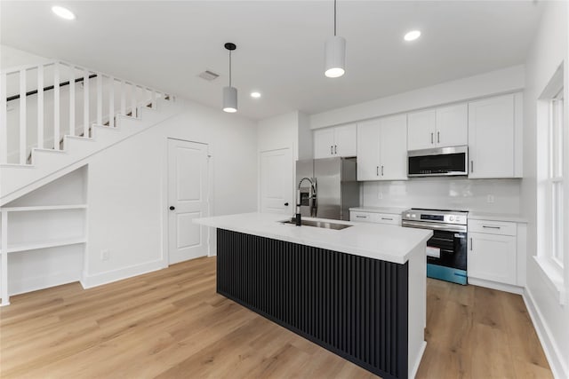 3327 Cornell St Unit A B, Houston, TX 77022 - kitchen with stainless steel appliances, white cabinets, light wood-style floors, pendant lighting, and an island with sink