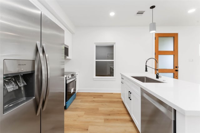 3327 Cornell St Unit A B, Houston, TX 77022 - kitchen featuring stainless steel appliances, white cabinetry, pendant lighting, light wood-style flooring, and light countertops