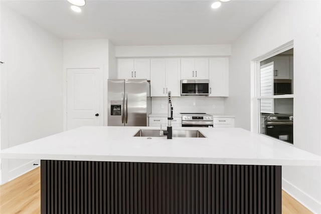 3327 Cornell St Unit A B, Houston, TX 77022 - kitchen with appliances with stainless steel finishes, white cabinets, light wood-style flooring, light countertops, and a kitchen island with sink