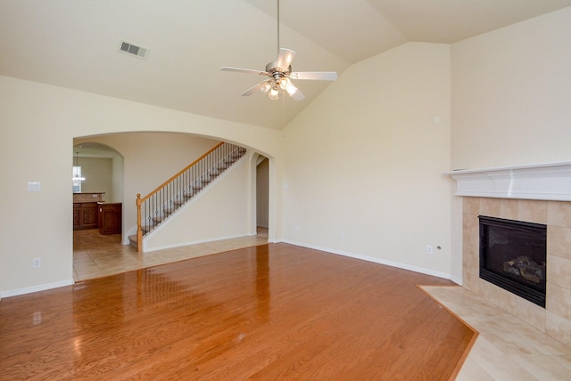 18702 Cypress Loch Dr, Spring, TX 77379 - unfurnished living room with vaulted ceiling, arched walkways, wood finished floors, a ceiling fan, and a tile fireplace