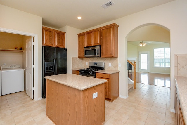 18702 Cypress Loch Dr, Spring, TX 77379 - kitchen with stainless steel appliances, arched walkways, backsplash, light tile patterned floors, and brown cabinetry