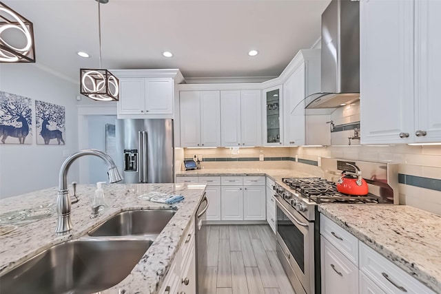 6 Caravelle Ct, Galveston, TX 77554 - kitchen featuring high quality appliances, wall chimney exhaust hood, white cabinets, tasteful backsplash, and decorative light fixtures