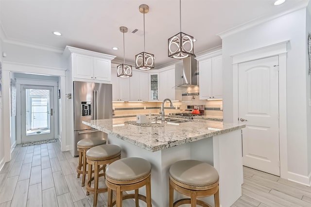 6 Caravelle Ct, Galveston, TX 77554 - kitchen with high end refrigerator, wall chimney range hood, decorative backsplash, white cabinetry, and recessed lighting