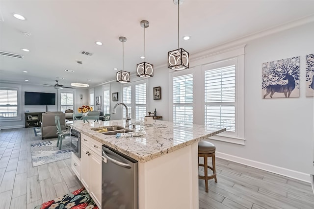 6 Caravelle Ct, Galveston, TX 77554 - kitchen featuring stainless steel appliances, light wood-style floors, a center island with sink, open floor plan, and light stone counters
