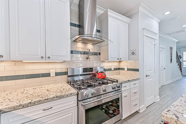 6 Caravelle Ct, Galveston, TX 77554 - kitchen with stainless steel gas stove, wall chimney exhaust hood, crown molding, white cabinets, and recessed lighting