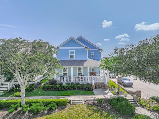 6 Caravelle Ct, Galveston, TX 77554 - view of front of property featuring covered porch, stairs, a shingled roof, and a front lawn