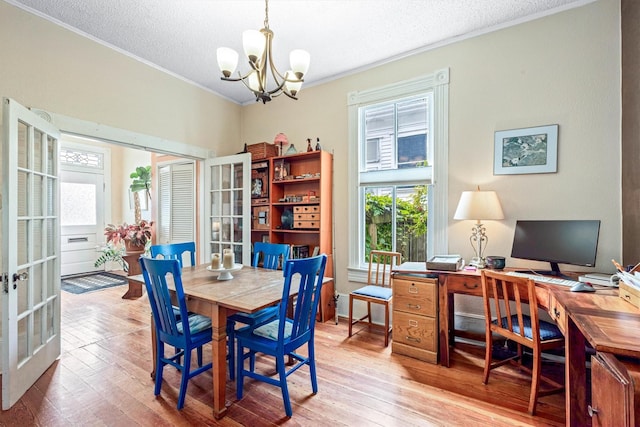 1611 34th St, Galveston, TX 77550 - dining space with a chandelier, crown molding, french doors, wood-type flooring, and a textured ceiling