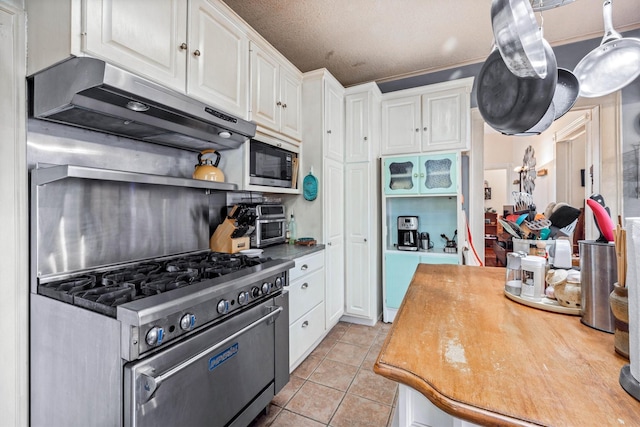 1611 34th St, Galveston, TX 77550 - kitchen featuring under cabinet range hood, black microwave, white cabinets, stainless steel range, and light tile patterned flooring