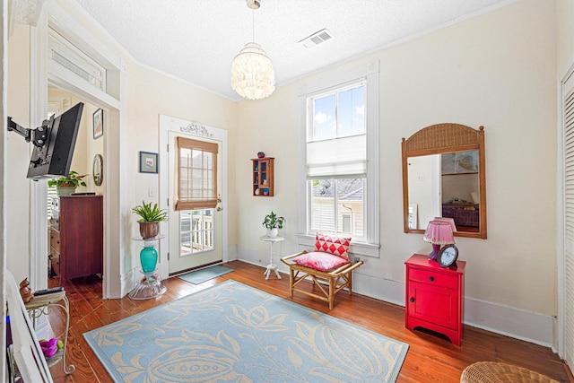 1611 34th St, Galveston, TX 77550 - foyer entrance with healthy amount of natural light, a chandelier, wood finished floors, a textured ceiling, and crown molding