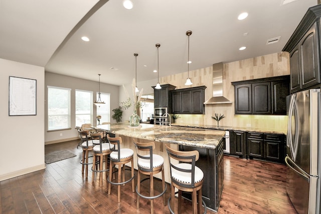 13810 Lake Prt, Cypress, TX 77429 - kitchen featuring appliances with stainless steel finishes, wall chimney range hood, a large island, dark wood-style flooring, and light stone counters