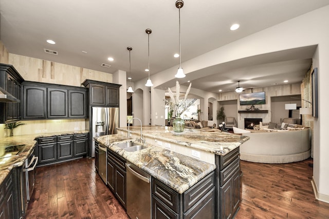 13810 Lake Prt, Cypress, TX 77429 - kitchen with stainless steel appliances, arched walkways, dark wood-style floors, a center island with sink, and recessed lighting