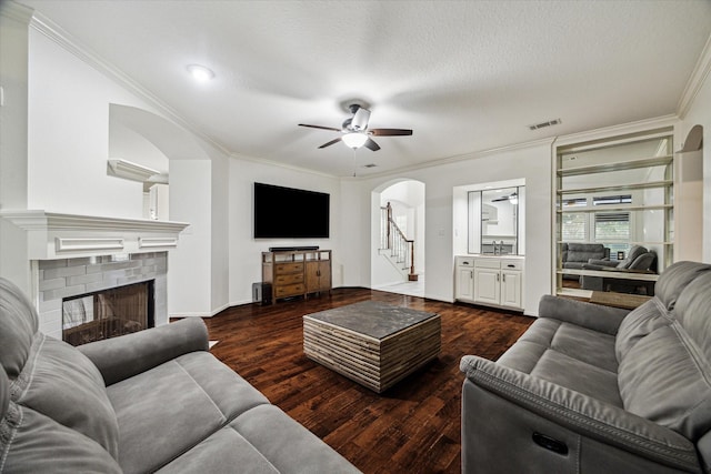 4107 Wentworth Dr, Fulshear, TX 77441 - living room featuring arched walkways, a ceiling fan, crown molding, a brick fireplace, and dark wood finished floors