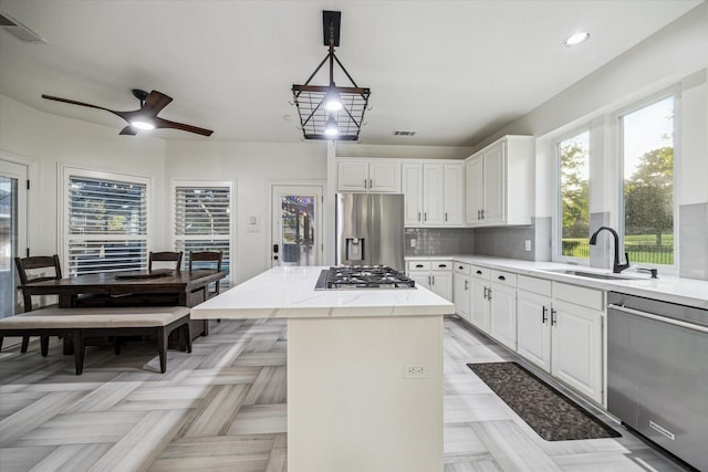 4107 Wentworth Dr, Fulshear, TX 77441 - kitchen with appliances with stainless steel finishes, a center island, backsplash, white cabinets, and light stone countertops