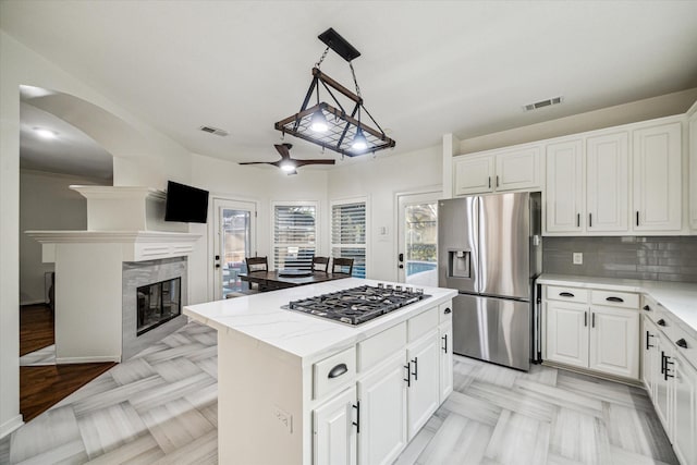 4107 Wentworth Dr, Fulshear, TX 77441 - kitchen featuring appliances with stainless steel finishes, a kitchen island, a ceiling fan, white cabinets, and light stone countertops
