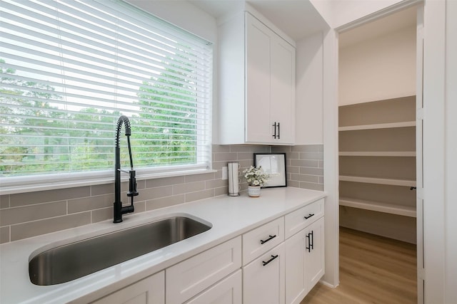 5703E Balbo St, Houston, TX 77091 - kitchen featuring decorative backsplash, white cabinetry, light countertops, and light wood finished floors