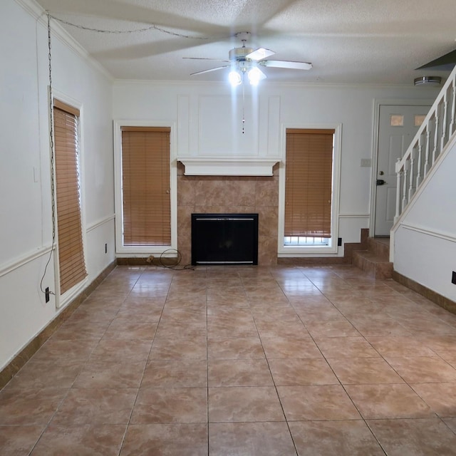3600 Jeanetta St Unit 1301, Houston, TX 77063 - unfurnished living room with ceiling fan, ornamental molding, a tiled fireplace, stairs, and light tile patterned floors