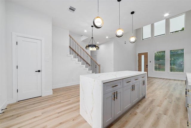 6715 England St, Houston, TX 77021 - kitchen with gray cabinets, light wood finished floors, pendant lighting, light stone counters, and a kitchen island