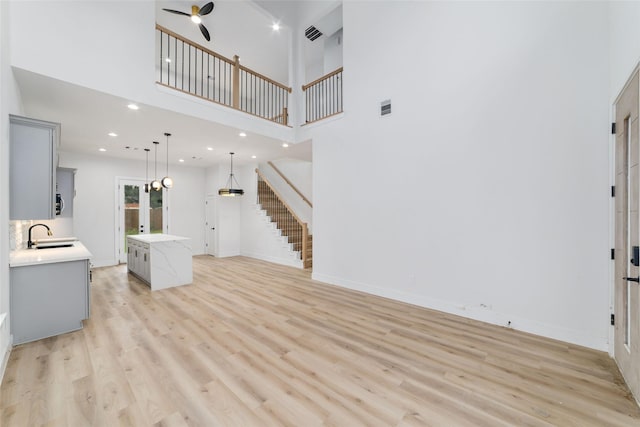 6715 England St, Houston, TX 77021 - unfurnished living room with stairway, light wood-style floors, a ceiling fan, a high ceiling, and recessed lighting