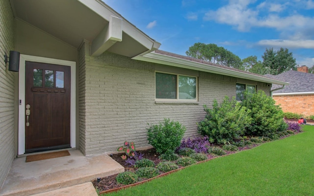 9818 Emnora Ln, Houston, TX 77080 - view of exterior entry with brick siding and a yard
