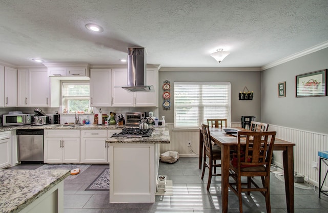 9818 Emnora Ln, Houston, TX 77080 - kitchen with wall chimney range hood, stainless steel appliances, plenty of natural light, wainscoting, and a textured ceiling