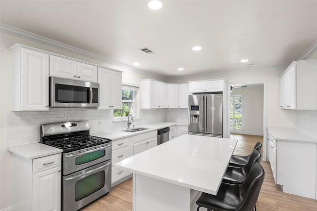 3815 Latma Dr, Houston, TX 77025 - kitchen with stainless steel appliances, a kitchen breakfast bar, a kitchen island, ornamental molding, and light countertops