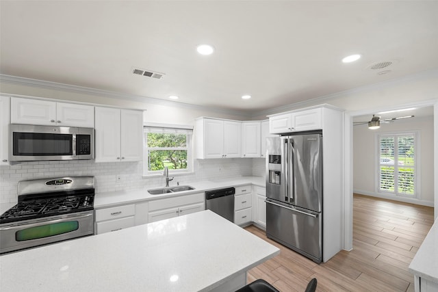 3815 Latma Dr, Houston, TX 77025 - kitchen featuring stainless steel appliances, healthy amount of natural light, crown molding, white cabinets, and decorative backsplash
