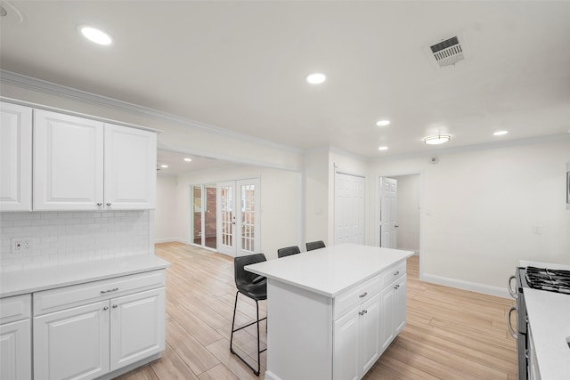 3815 Latma Dr, Houston, TX 77025 - kitchen featuring french doors, a kitchen bar, stainless steel range with gas stovetop, ornamental molding, and backsplash