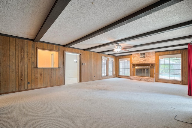 2823 W Pebble Beach Dr, Missouri City, TX 77459 - unfurnished living room featuring a textured ceiling, beamed ceiling, wooden walls, carpet floors, and a fireplace