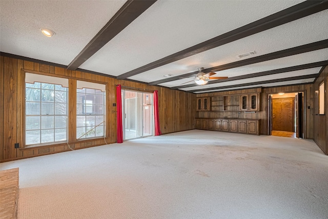 2823 W Pebble Beach Dr, Missouri City, TX 77459 - unfurnished living room with wood walls, light carpet, beamed ceiling, a textured ceiling, and ceiling fan