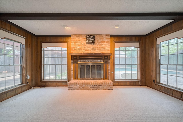 2823 W Pebble Beach Dr, Missouri City, TX 77459 - unfurnished living room with a textured ceiling, beamed ceiling, wooden walls, a brick fireplace, and carpet floors