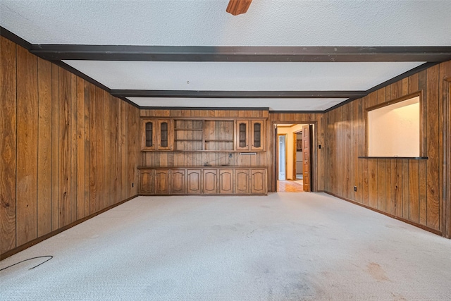 2823 W Pebble Beach Dr, Missouri City, TX 77459 - spare room featuring beam ceiling, wood walls, light colored carpet, and a textured ceiling