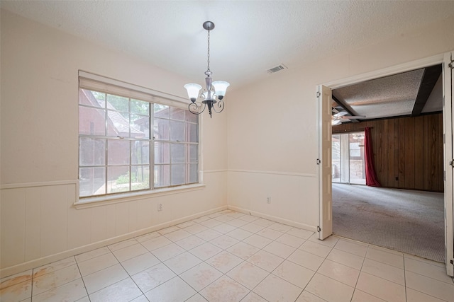 2823 W Pebble Beach Dr, Missouri City, TX 77459 - unfurnished room with a chandelier, a textured ceiling, light tile patterned flooring, wood walls, and a ceiling fan
